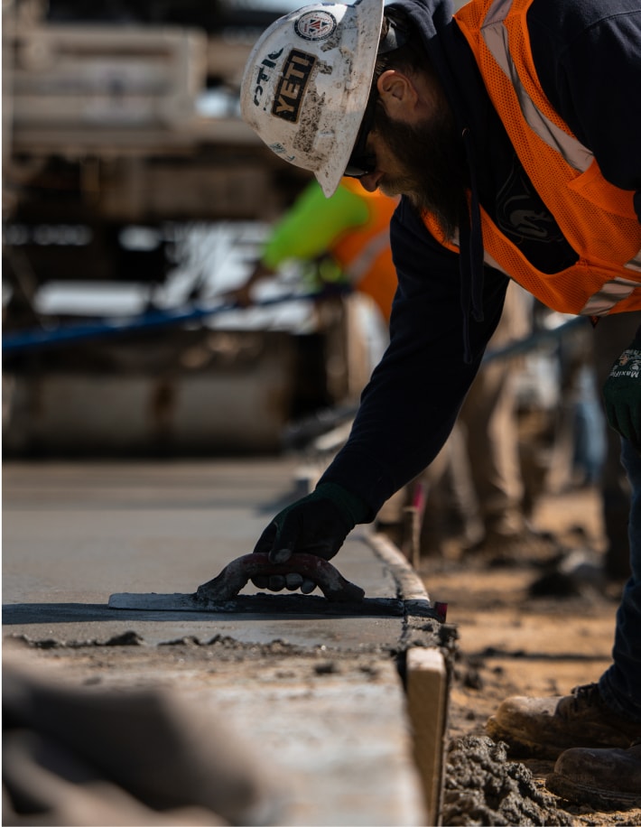 Construction worker smoothing concrete with a hand trowel