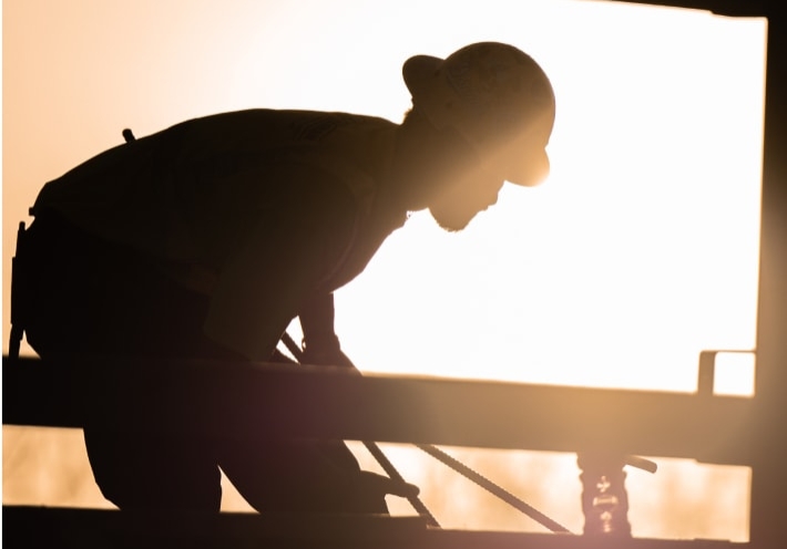 Silhouetted construction worker with sun behind them